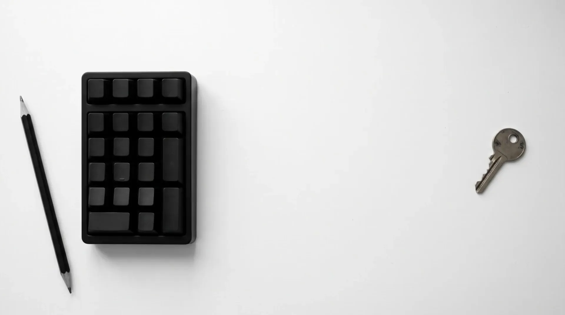 Illustrative top-down desk with a black keypad, brass key and sharpened pencil